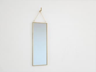 壁に掛けられたハンギングミラーオブロング ゴールド