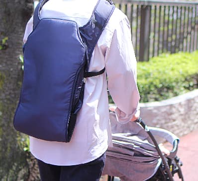 ベビーキャリアを背負ってベビーカーを押す人