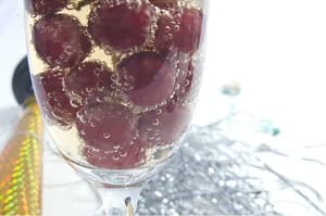 グラスに入った炭酸水と紫色の丸い果実