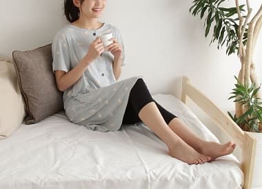 アニマルチュニック&レギンスパジャマ グレーを着てベッドでくつろぐ女性