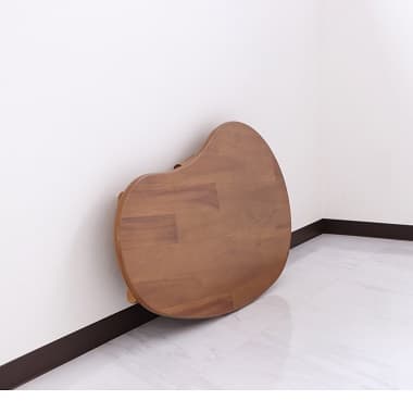 折りたたんで壁に立てかけられた折れ脚テーブル(豆型)