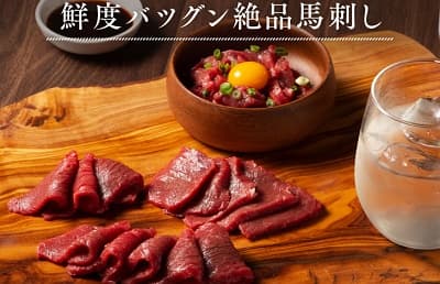 馬刺しと卵黄の乗ったユッケとグラスに入った焼酎 鮮度バツグン絶品馬刺し