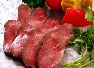 野菜と一緒に盛られた8枚にスライスされた牛タンローストビーフ