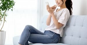 ソファでスマホを見る女性